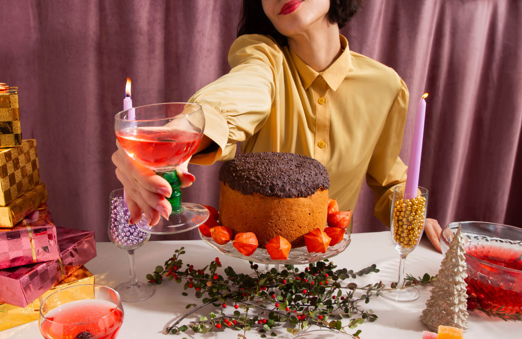 Woman in front of a festive holiday table, holding a drink