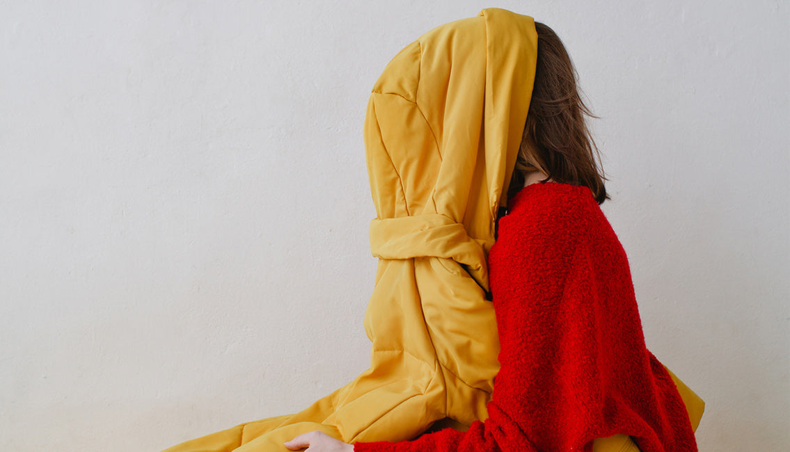 woman sitting with jacket covering her face