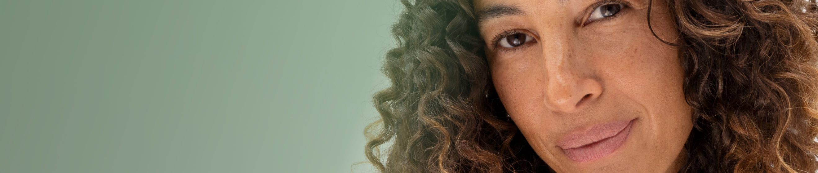 Close-up of a woman with curly hair against a plain background