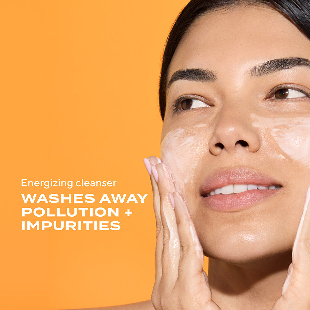 woman lathering cleanser product on face. text states energizing cleanser washes away pollution + impurities